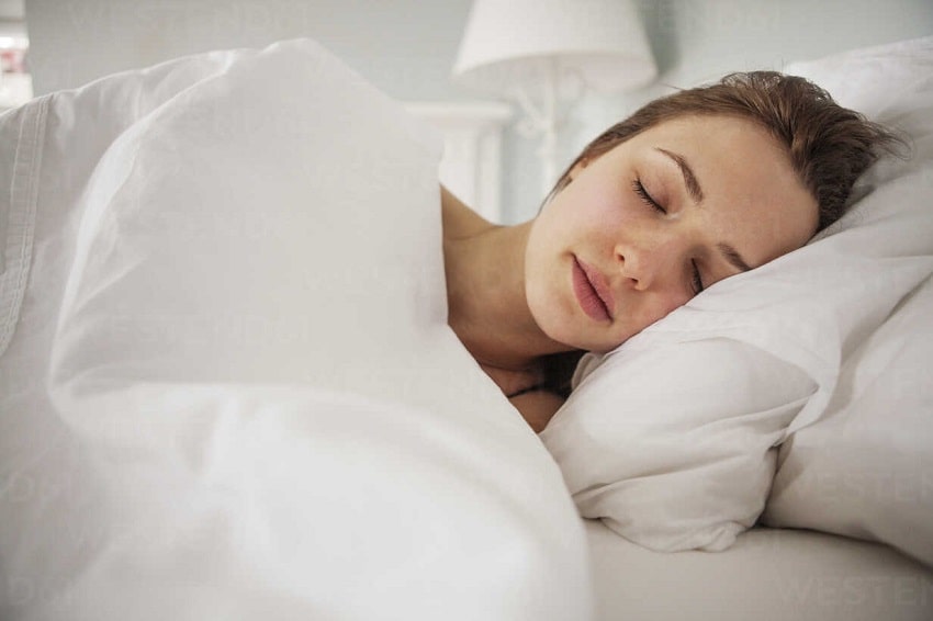 یک زن خوابیده با دو بالشت برای درمان سیاهی دور چشم